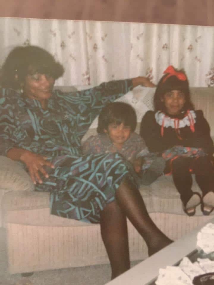 A young Siham sitting on a couch with her brother and mother in South Africa.