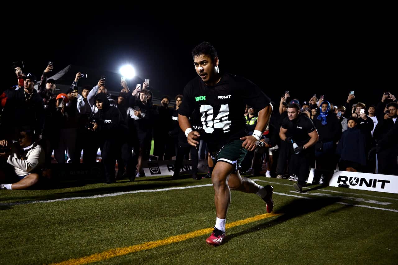 A man is running on the green field as people watch and cheer around him.