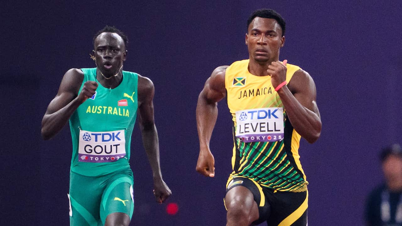 Two men running, one wearing a green shirt with the word 'Australia', and another wearing a yellow 'Jamaica' shirt.