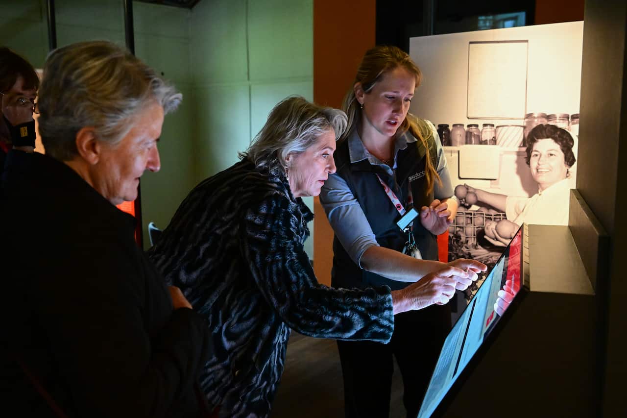 A woman operates a touch screen with the help of another woman
