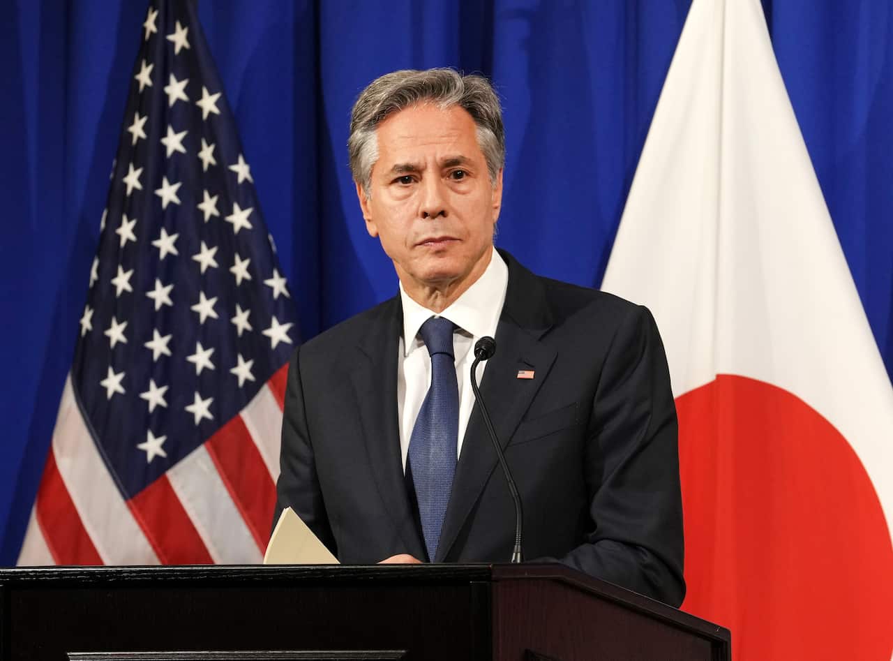 US Secretary of State Antony Blinken stands at a lectern in front of US and Japanese flags. 
