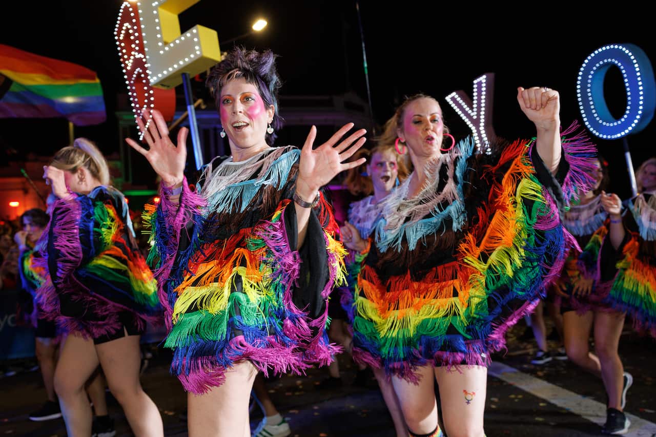 Participants wearing rainbow outfits march in Sydney Mardi Gras