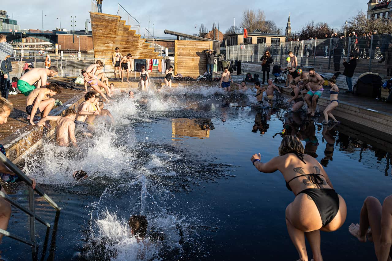 People in swimwear dive into an outdoor pool