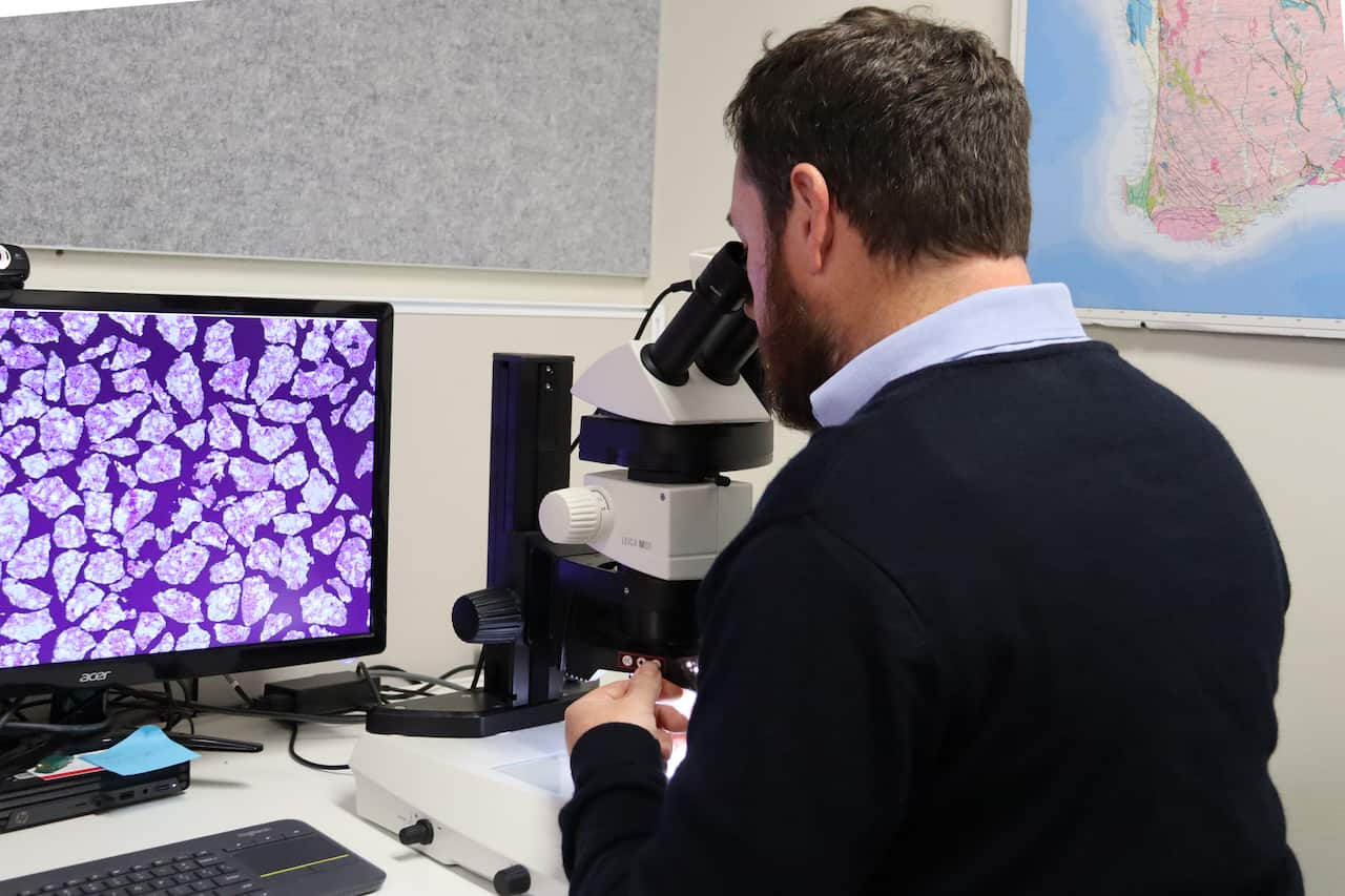 A man studies rocks under the microscope in a laboratory.