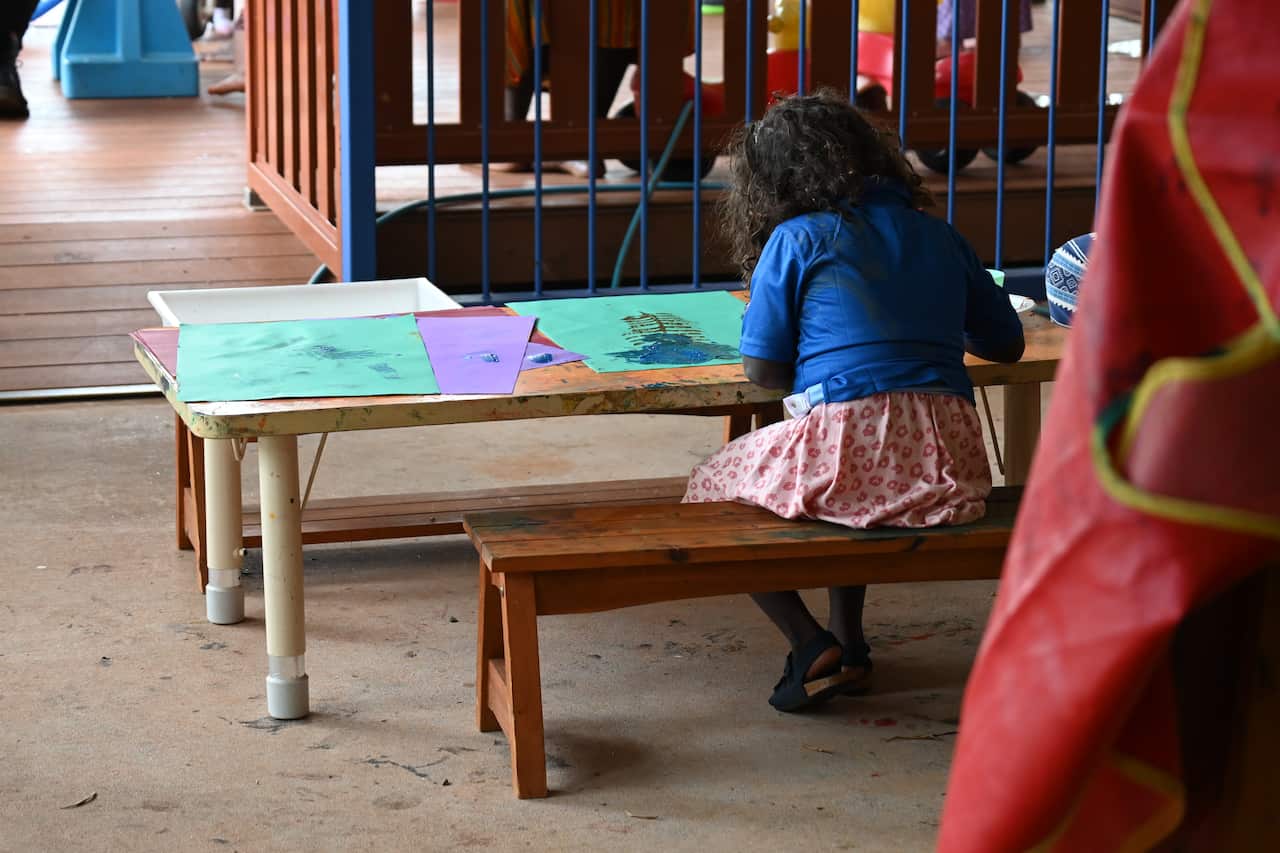 A little girl works on a painting at the Families As First Teachers (FAFT) early learning centre in Gunbalanya