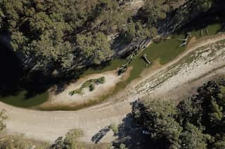 An ariel photograph of the Darling River, showing green trees and murky green water which has receded to show sand.