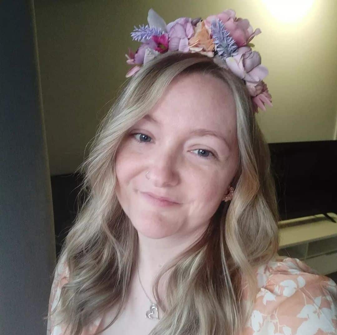 A woman with blonde hair wearing a floral wreath. 