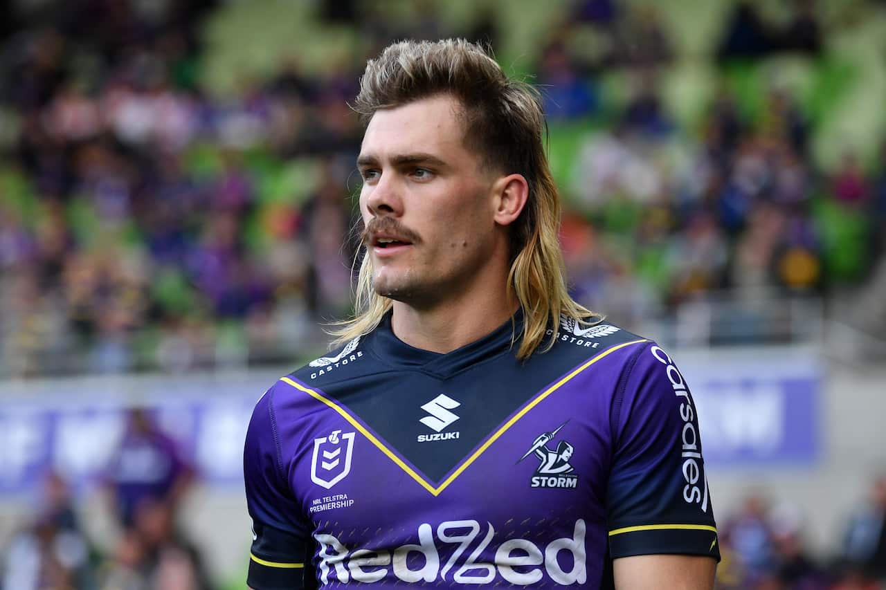 Ryan Papenhuyzen wears a Melbourne jersey. He has a long mullet and moustache. 