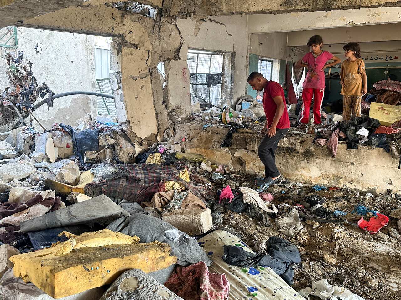 People standing amidst rubble of a heavily damaged building.