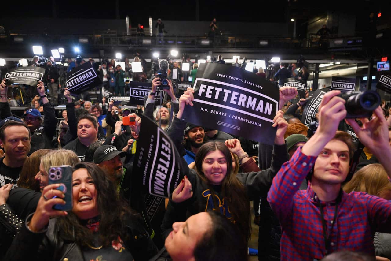 A crowd cheering. Some are holding signs that read: "FETTERMAN: Every County. Every Vote."