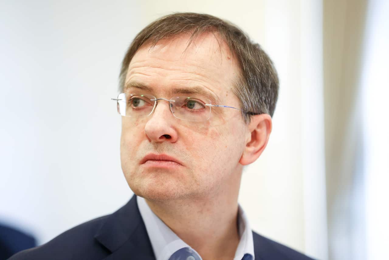 A man with short hair and wearing glasses looking to the side.