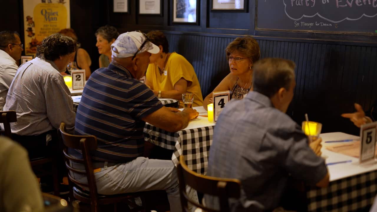 Older-aged people sitting at tables at a speed dating event.