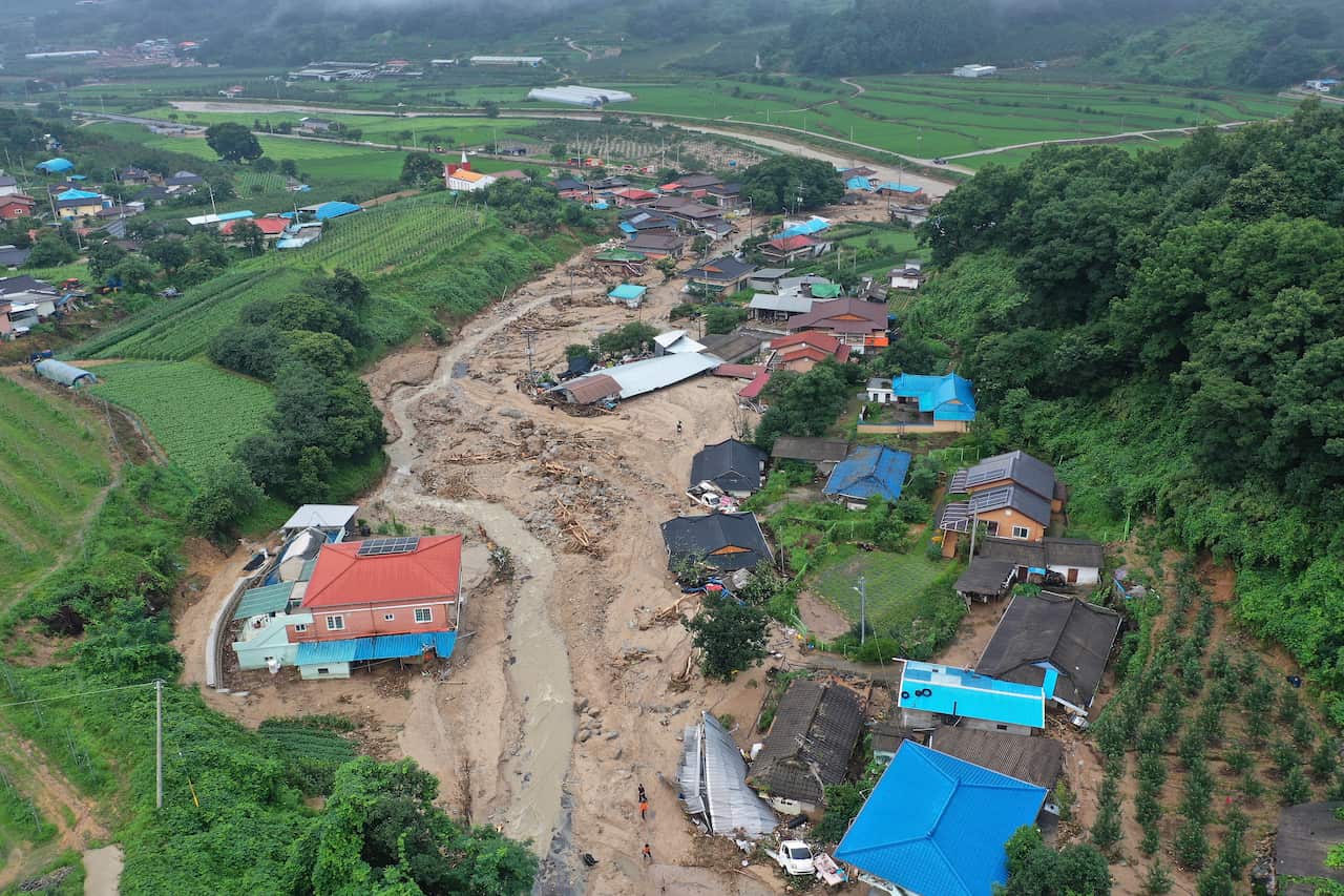An overhead shot shows houses submerged by a landslide