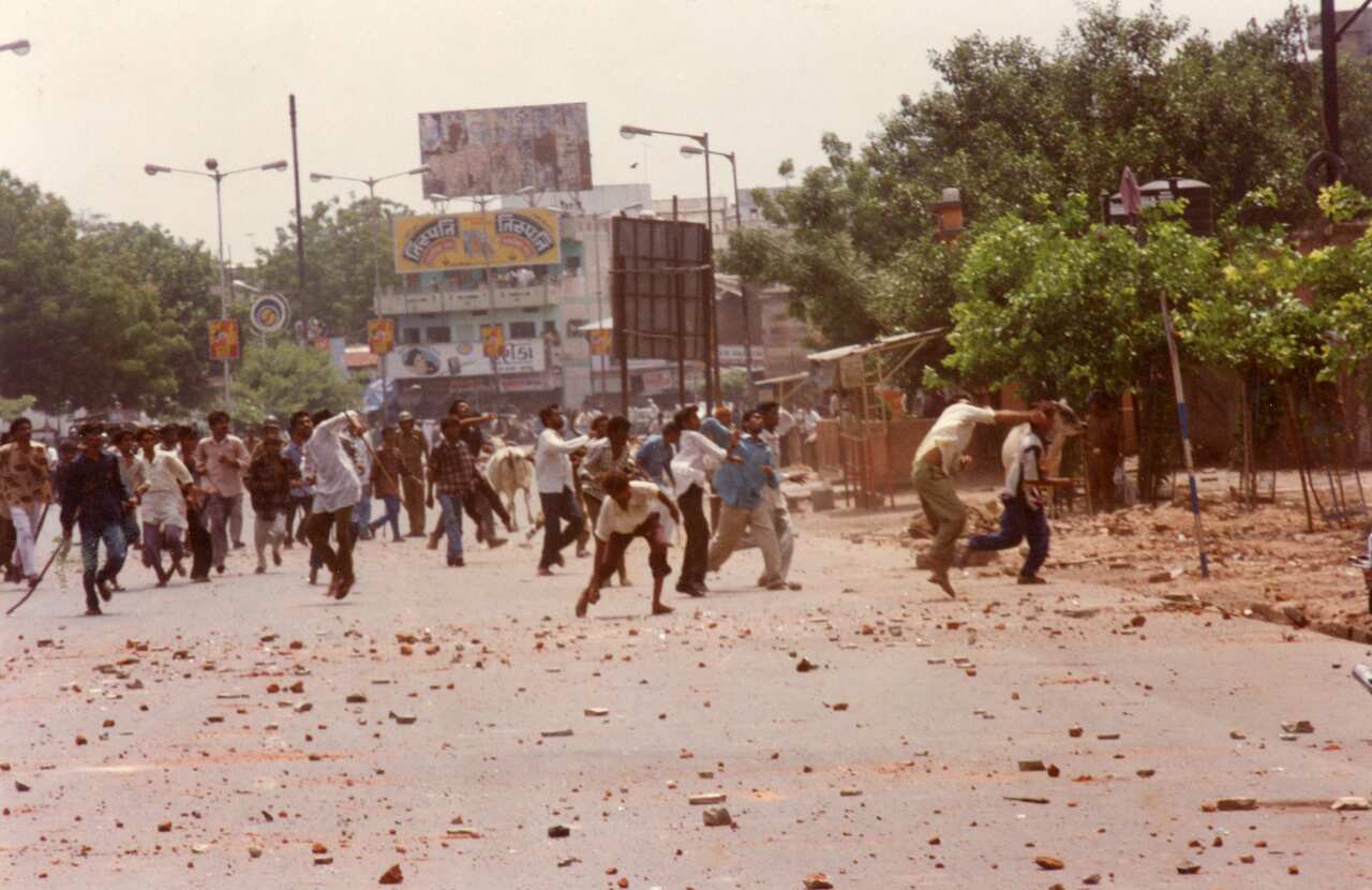 An old photo showing a large group of men picking up rocks and throwing them