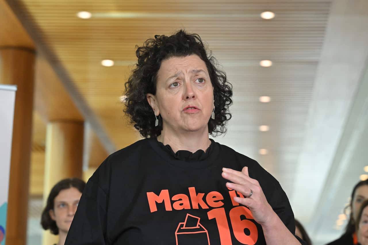 A middle aged woman in a black t-shirt, gesturing with her left hand.