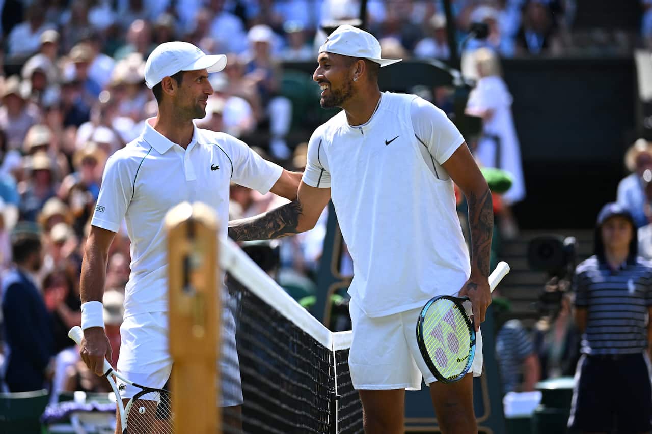 Two men speaking while standing at a tennis net.