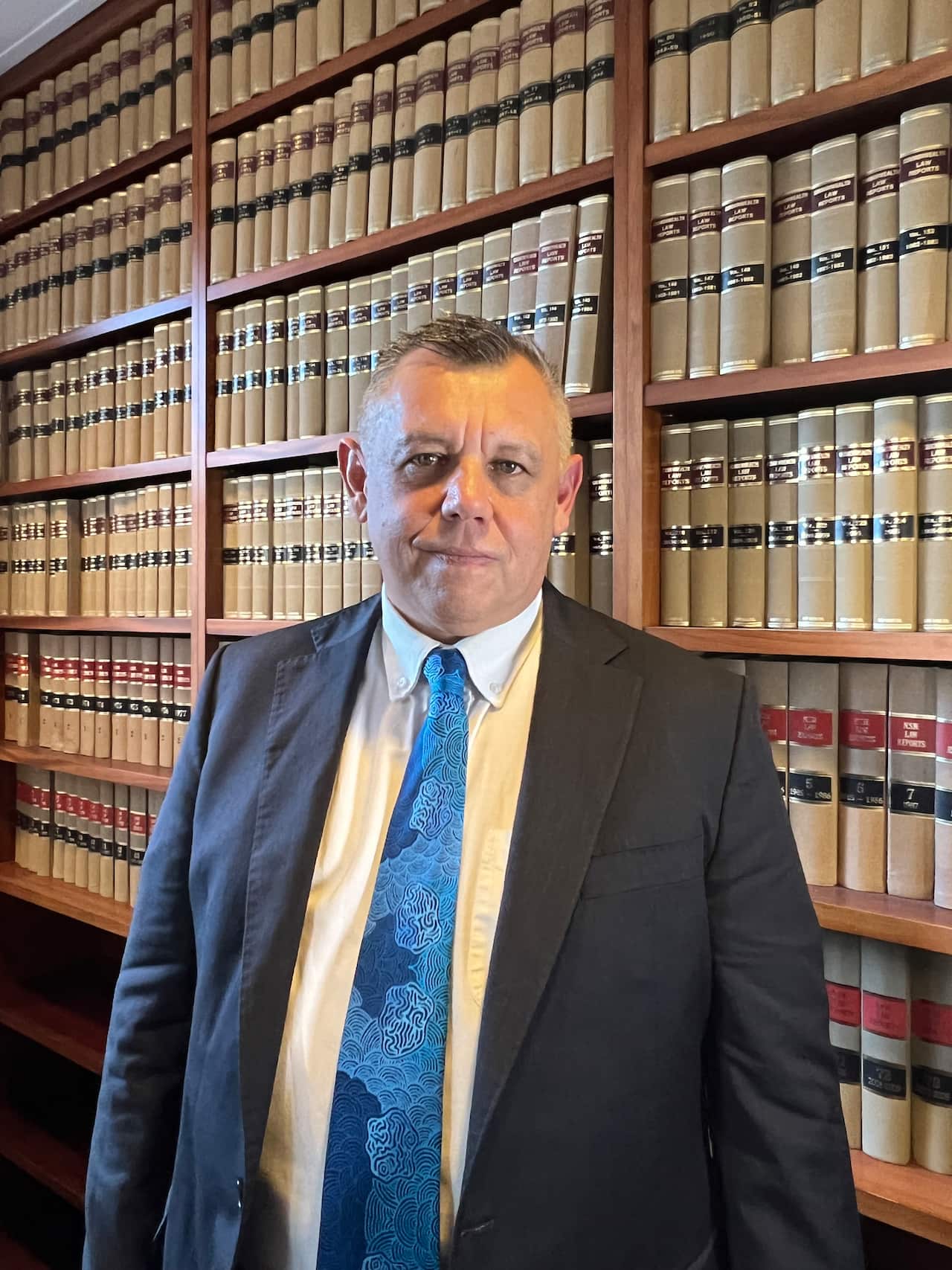 A man standing in front of a bookcase of legal books