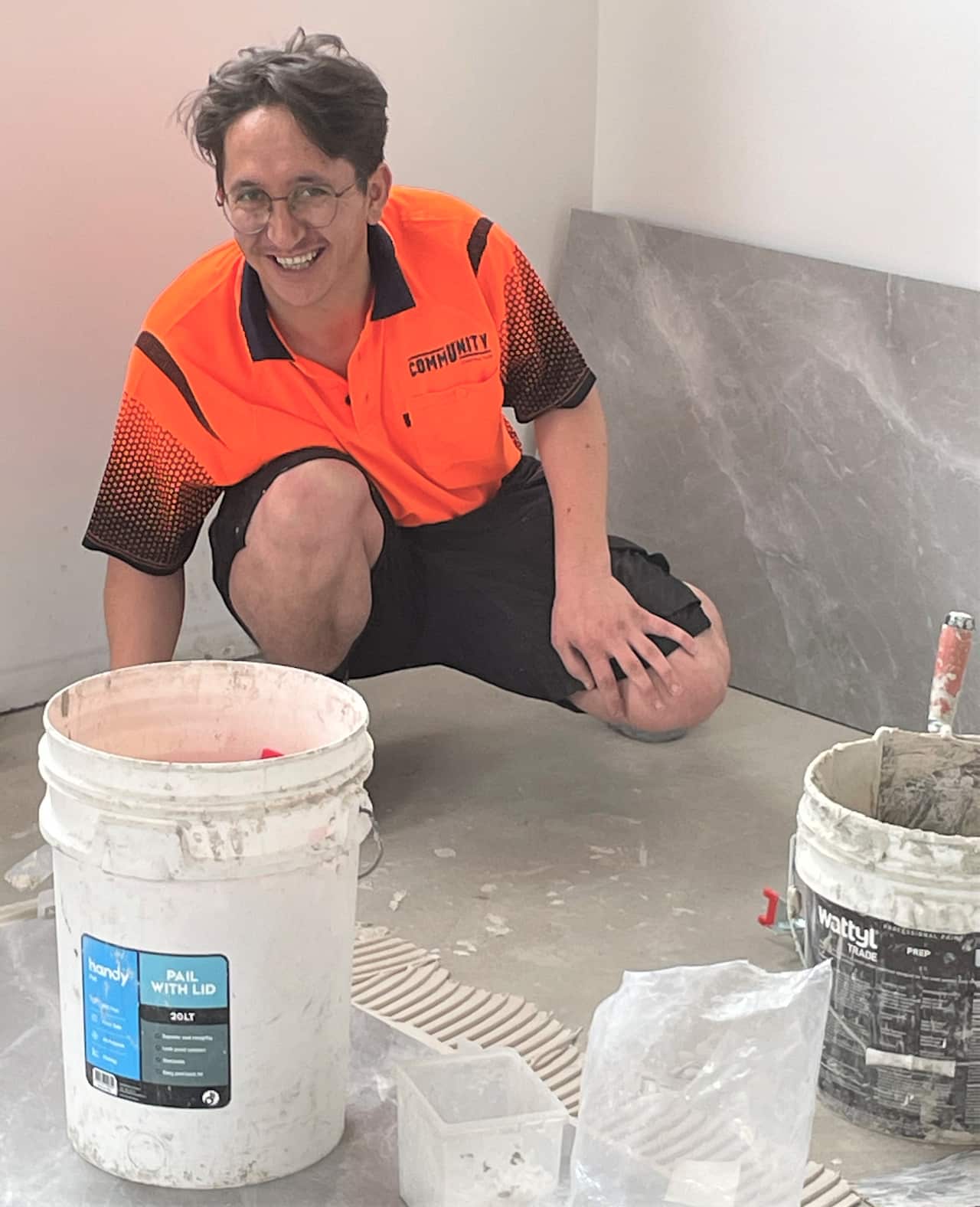 Mujtaba Folad crouching at work tiling a new home in Sydney.