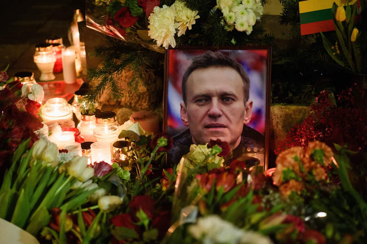 Flowers and candles place around a framed photo of a man.