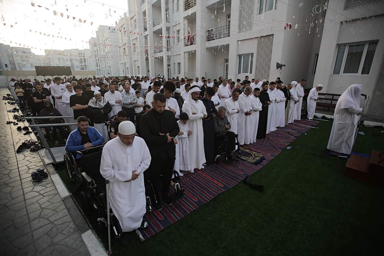 A group of Muslims praying outside in a city