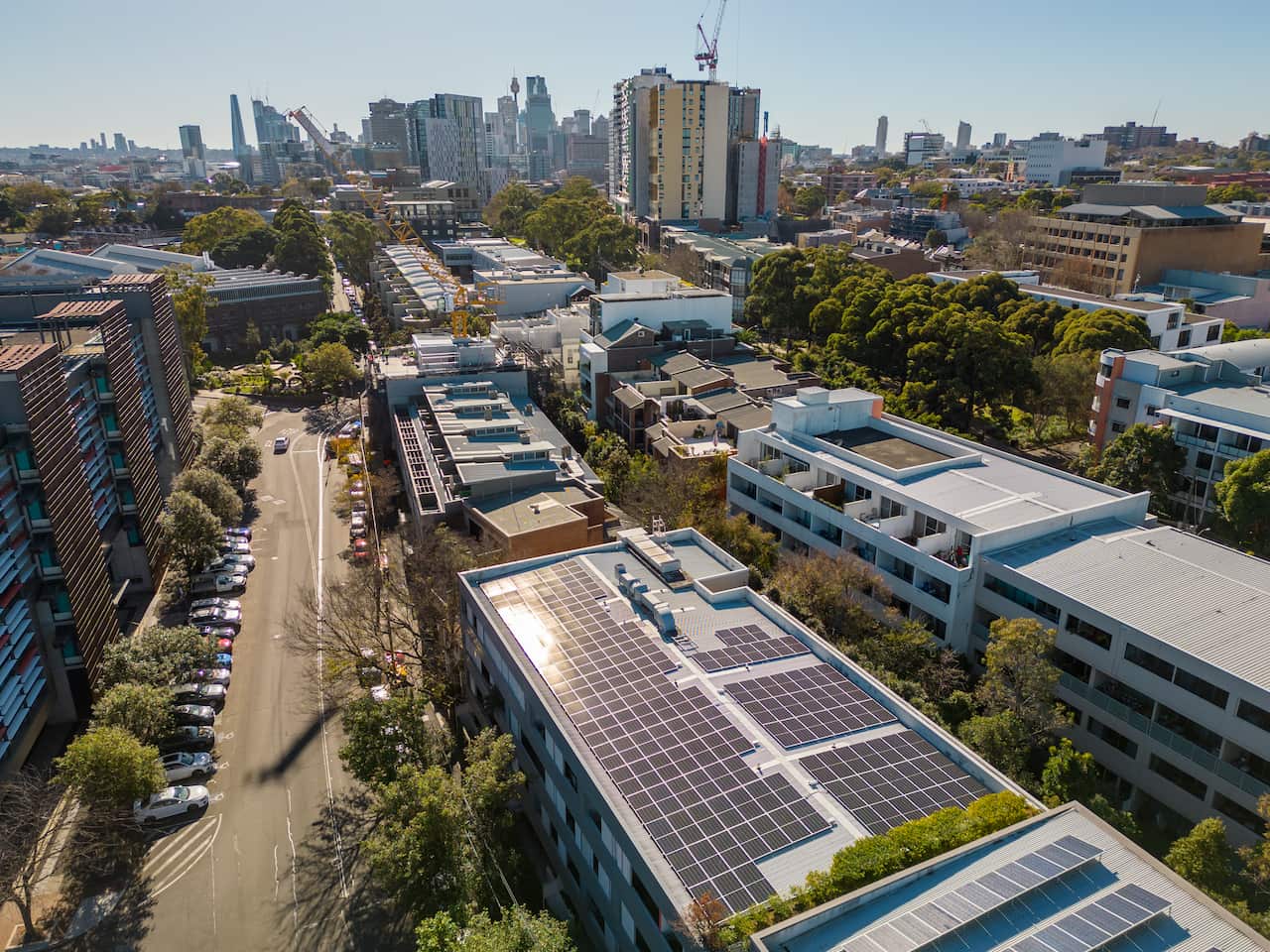 An overhead photo shows the roof of an apartment building covered in solar panels