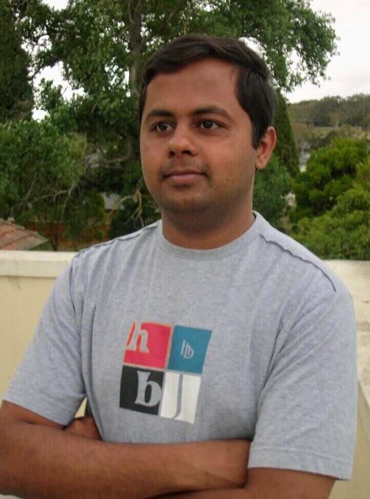 A man wearing a grey t shirt and folding his arms.