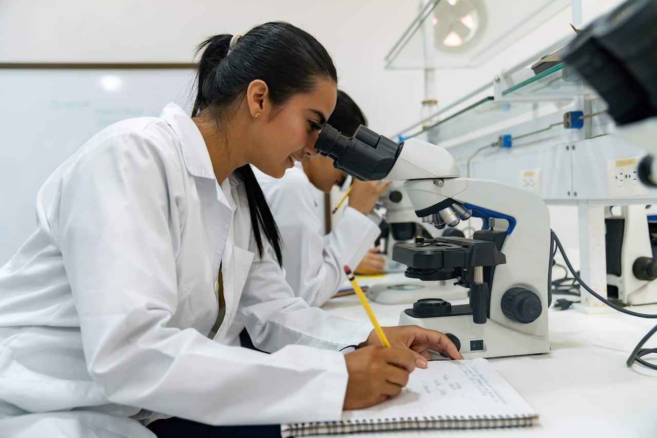 Female student looking through a microscope at the university lab