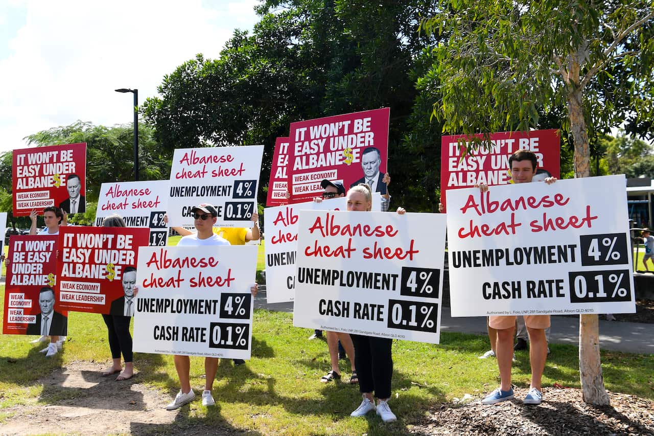 A group of protesters is seen near where Australian Opposition leader Anthony Albanese holds a press conference after inspecting a street affected by recent flooding events in the Brisbane suburb of Auchenflower.