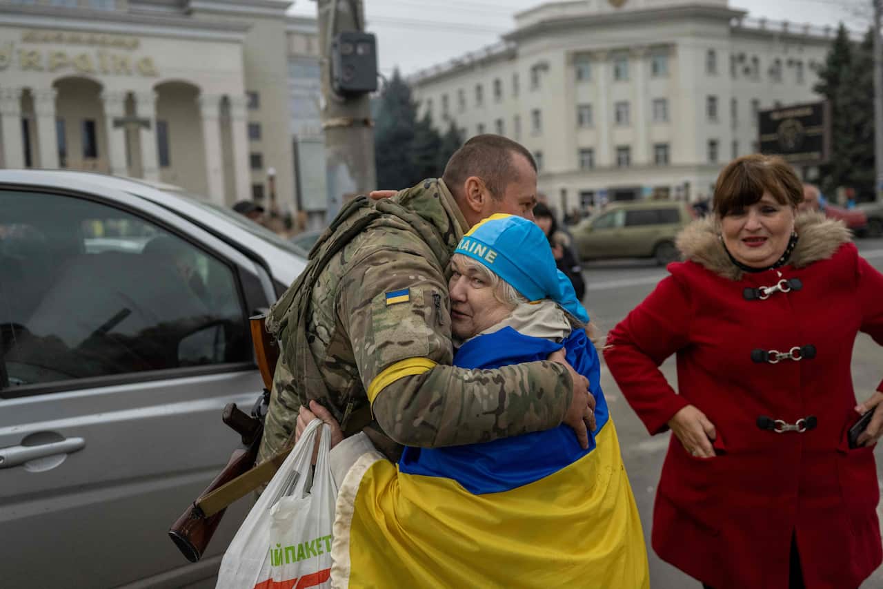 A woman, wearing the Ukrainian flag, hugs a Ukrainian soldier in central Kherson