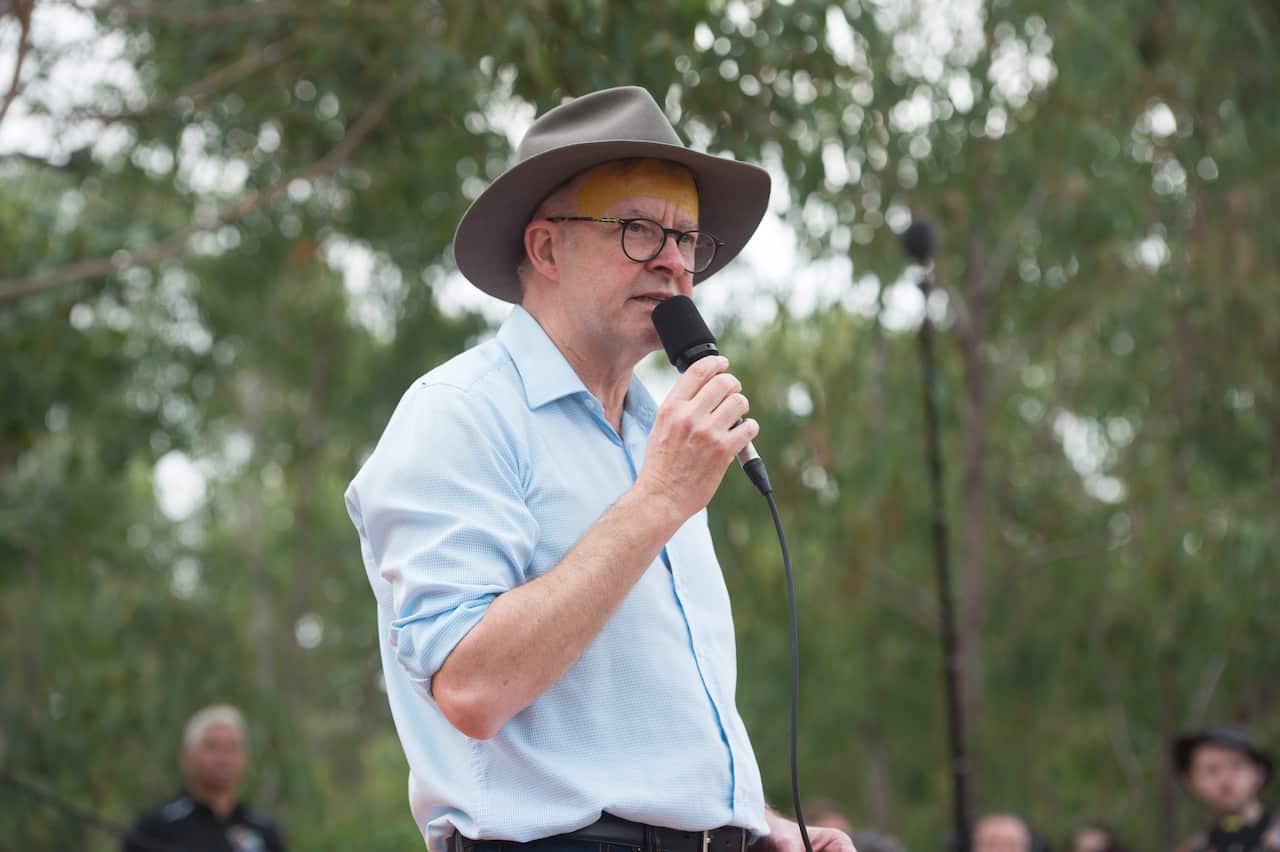 A man speaking into a microphone wearing an akubra hat