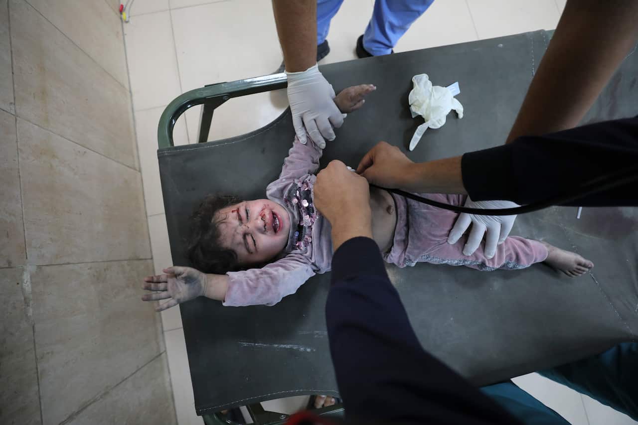 A child on a stretcher is treated for wounds