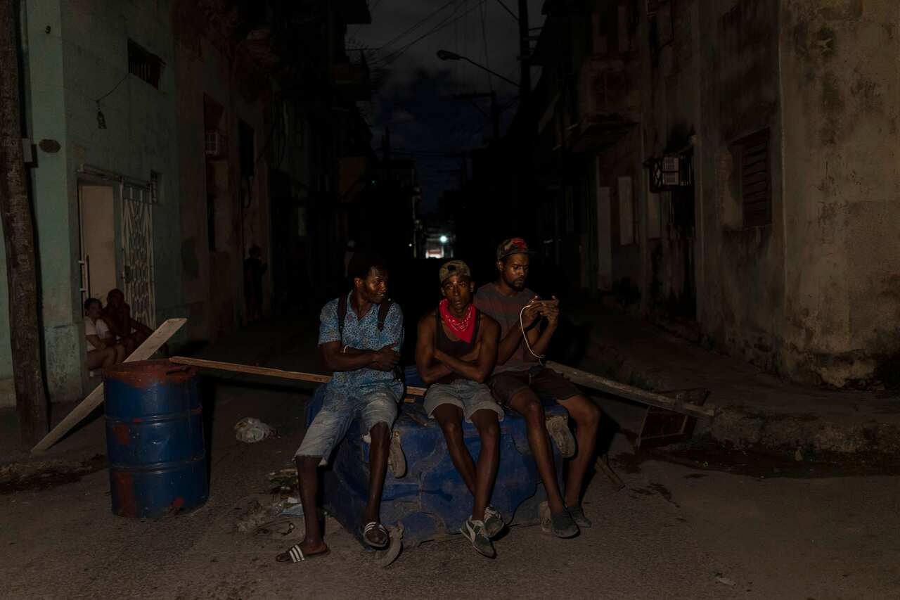 Los residentes se paran junto a una barricada que levantaron para bloquear una carretera durante una protesta que pedía el restablecimiento de los servicios eléctricos después de cuatro días de cortes de energía causados ​​por el huracán Ian, en La Habana, Cuba, el viernes 30 de septiembre de 2022.