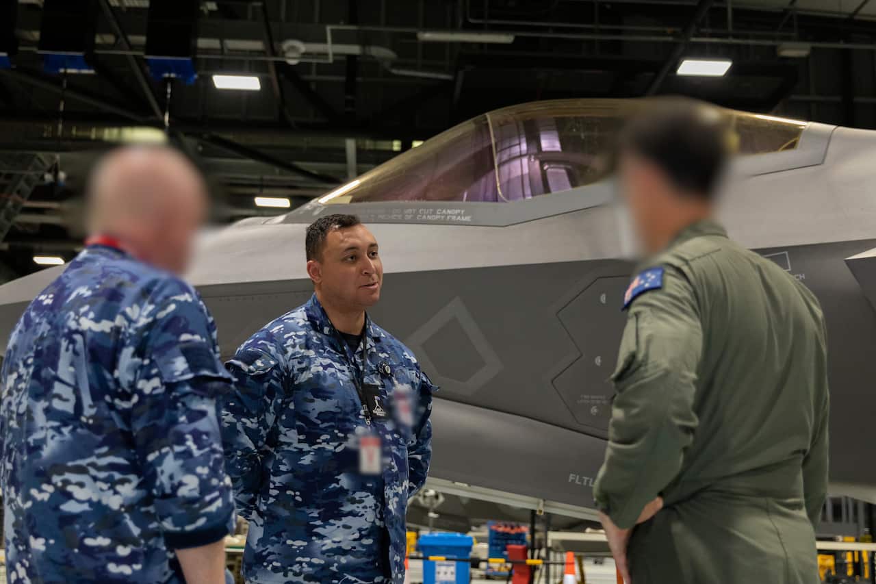 A man in air force uniform talks to other men in uniform.