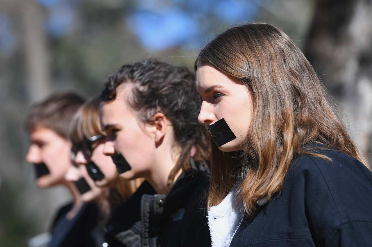 Five protesters with tape over their mouths.