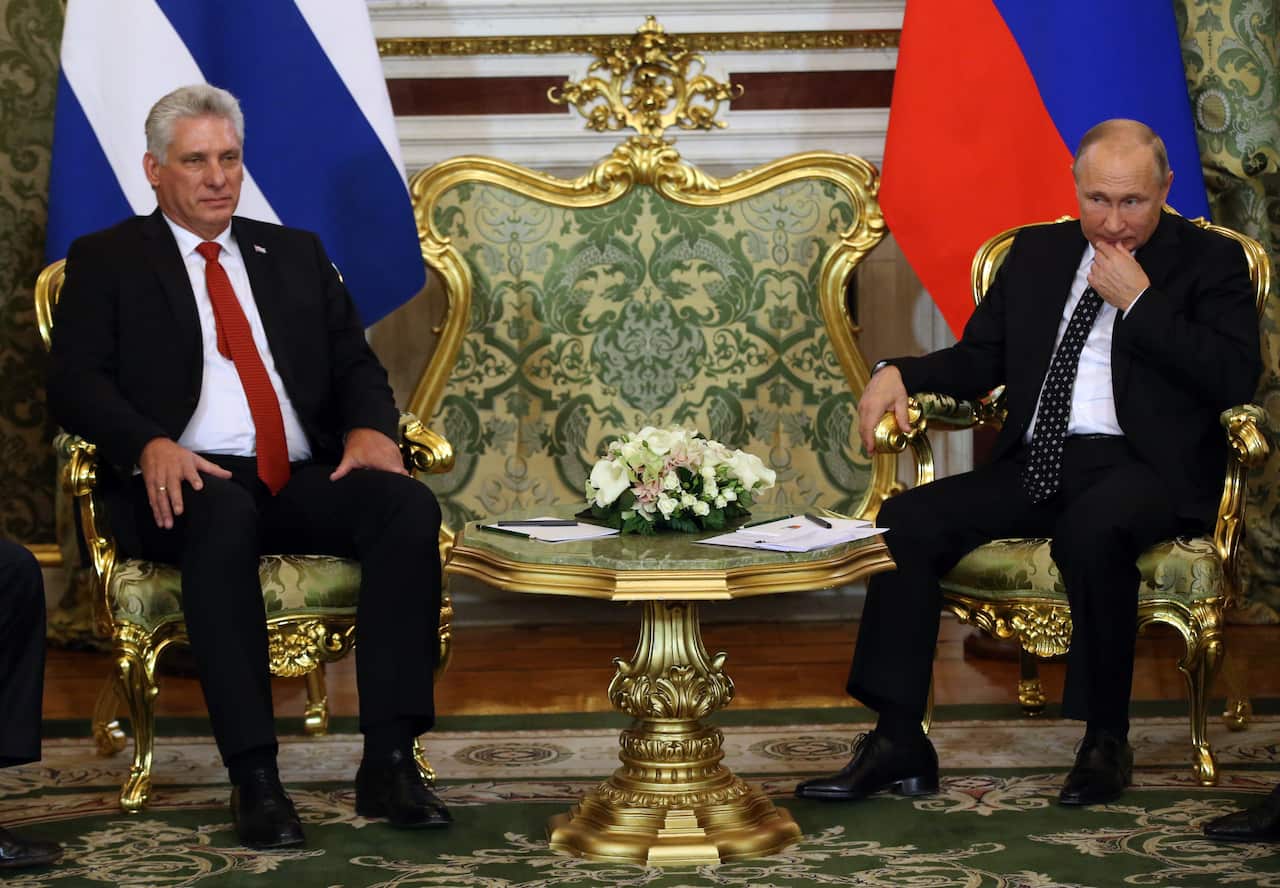 Russian President Vladimir Putin (right) and Cuban President Miguel Diaz-Canel (left) wearing suits sitting in ornate chairs inside.
