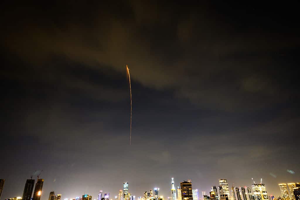 A ballistic missiles falls from the night sky over high-rise city buildings.