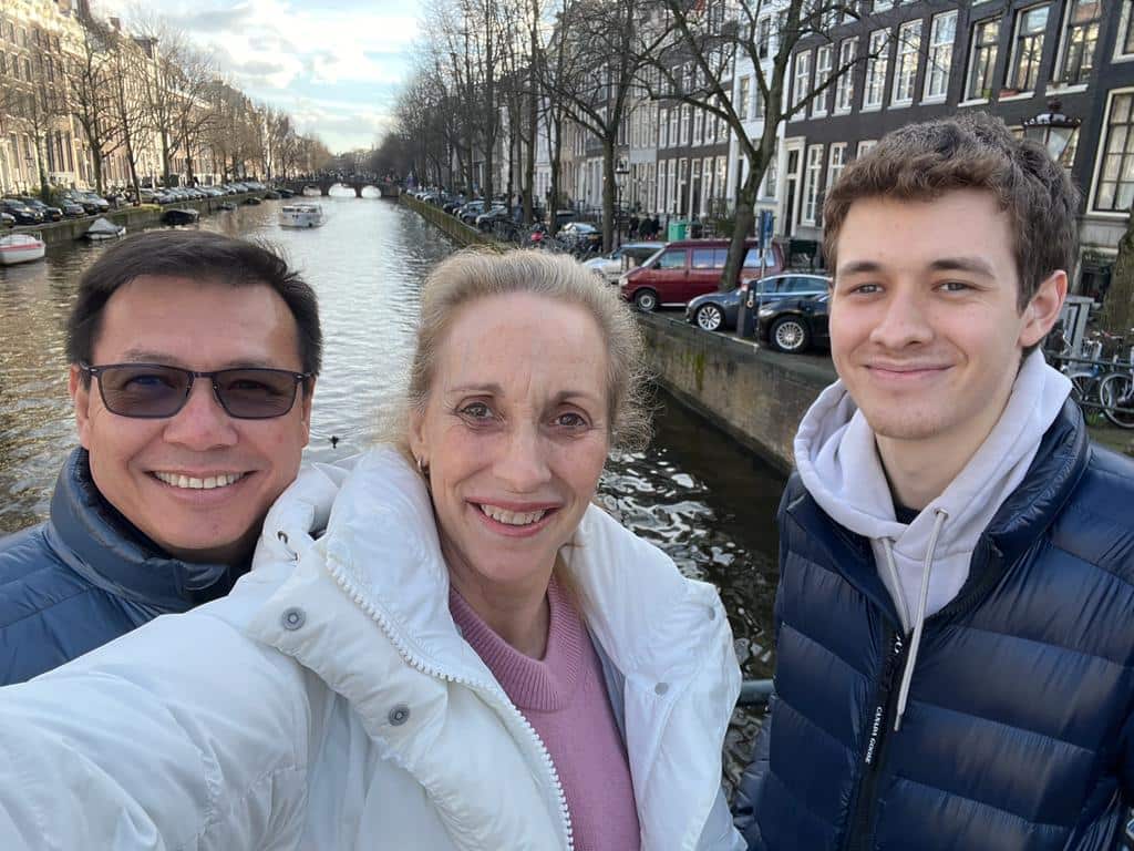 A man and woman stand on a bridge alongside a younger man. 