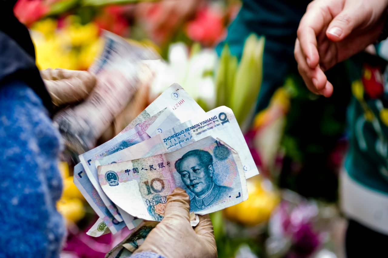 Close-up of a transaction at a street side flower market. The person is holding Chinese currency