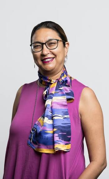 picture of a smiling women wearing glasses and long pink shirt