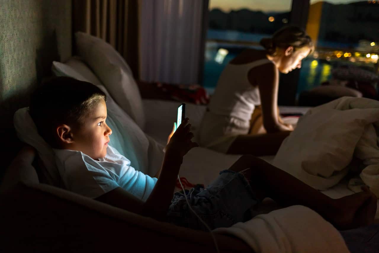 A woman and a young boy lit by screens at night.
