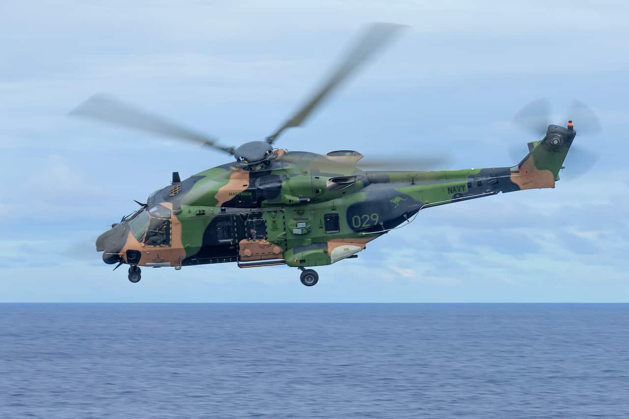 An Australian Army MRH-90 Taipan helicopter flies over water 