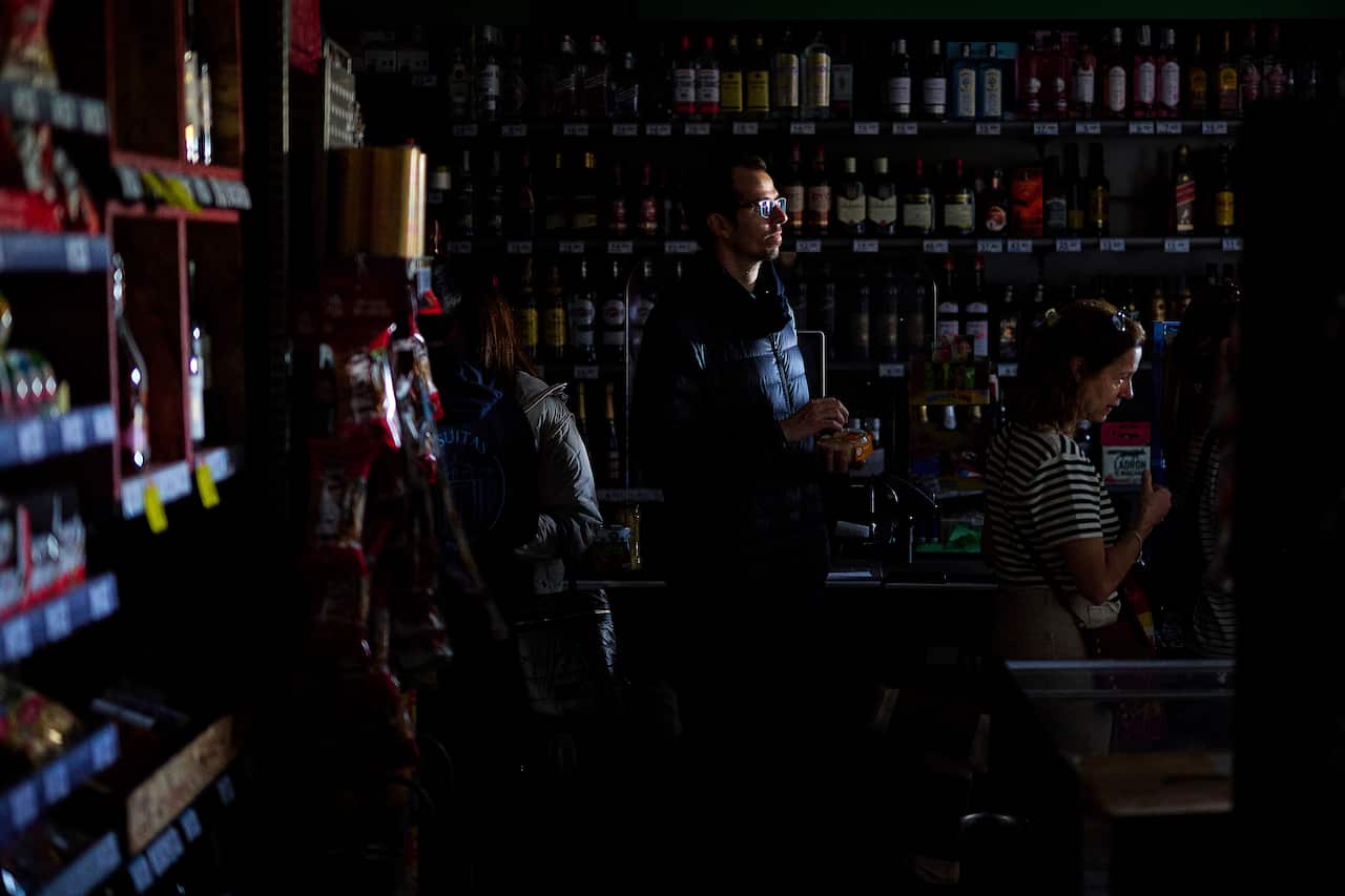 A queue of people in the dark inside a supermarket.