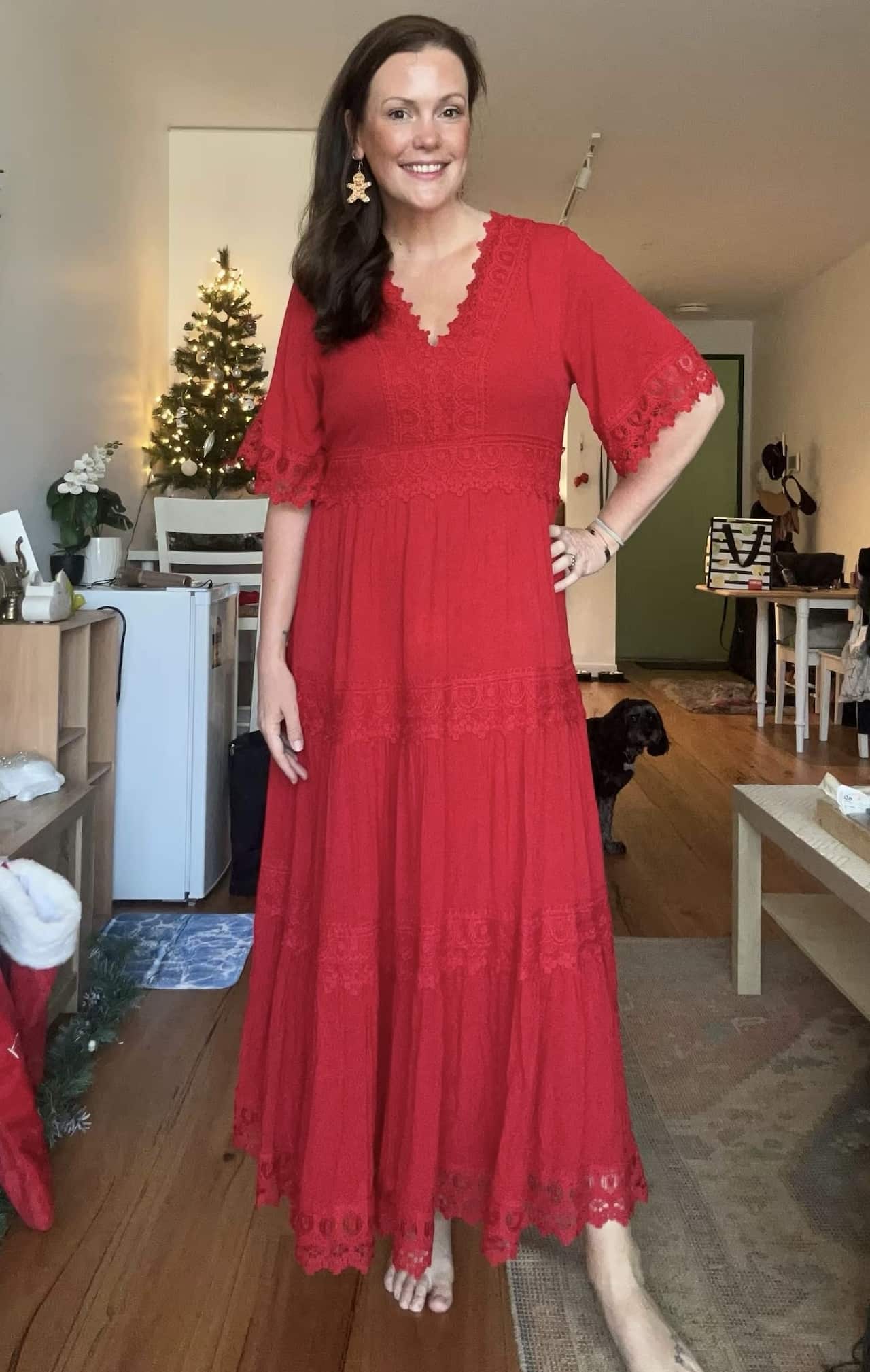 A woman with long dark hair posing for a photo inside while wearing a long red dress