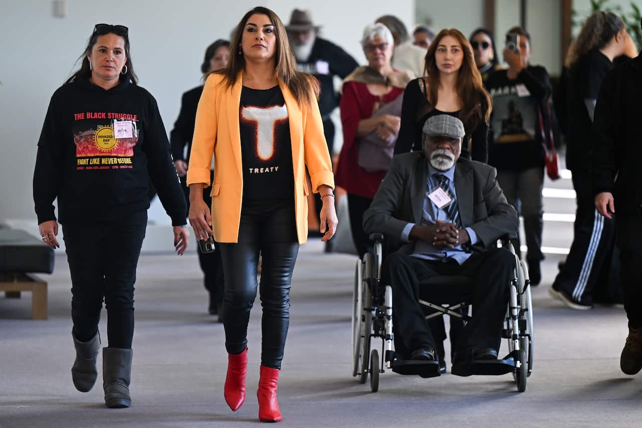 Lidia Thorpe walks with a group of people through parliament.