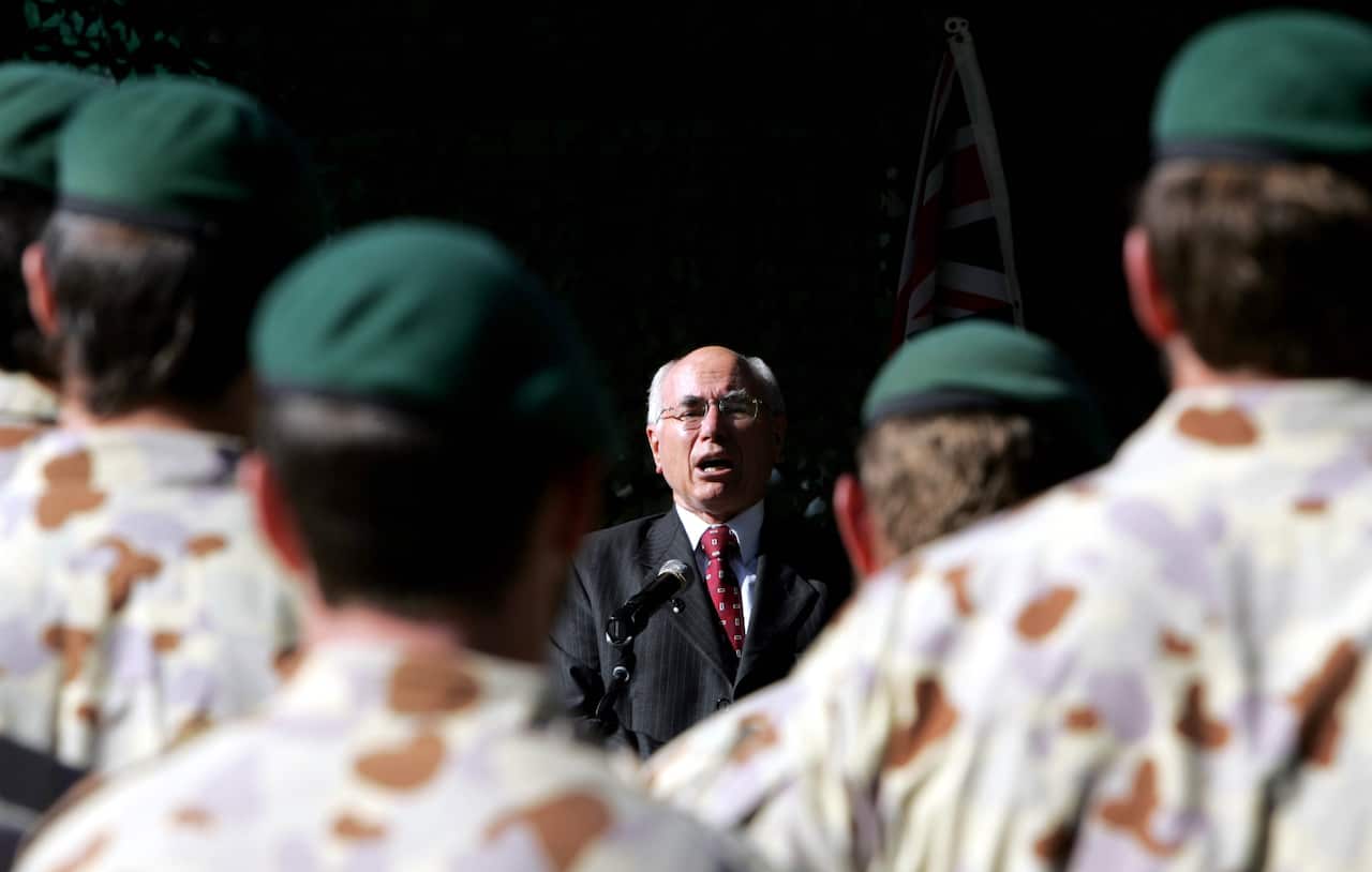 A man in a suit is addressing military personnel.