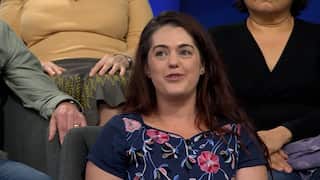 a closeup of a young woman with brown hair in a floral dress in a studio audience