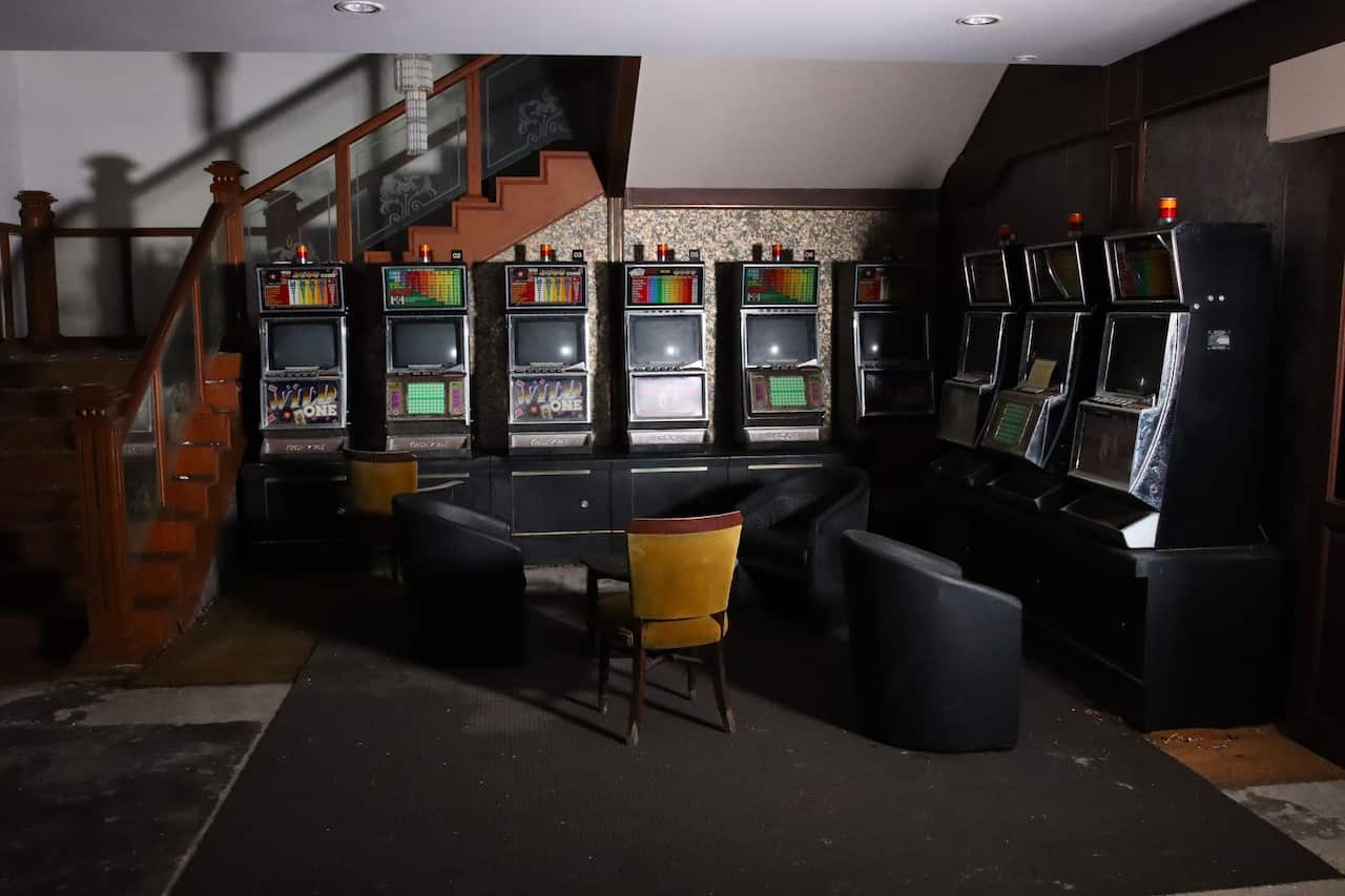 Nine slot machines in a dark room, with a staircase beside it.