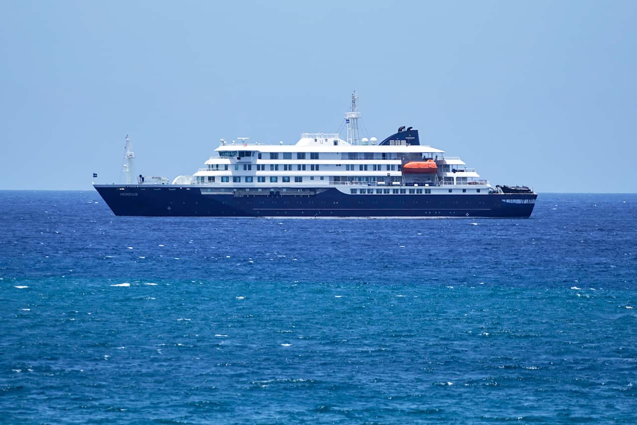 A small cruise ship with a blue hull in the ocean