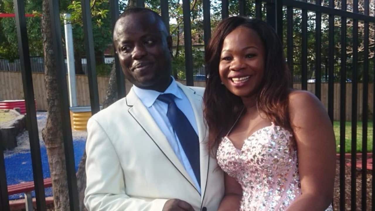 a smartly dressed couple smile in front of a playground