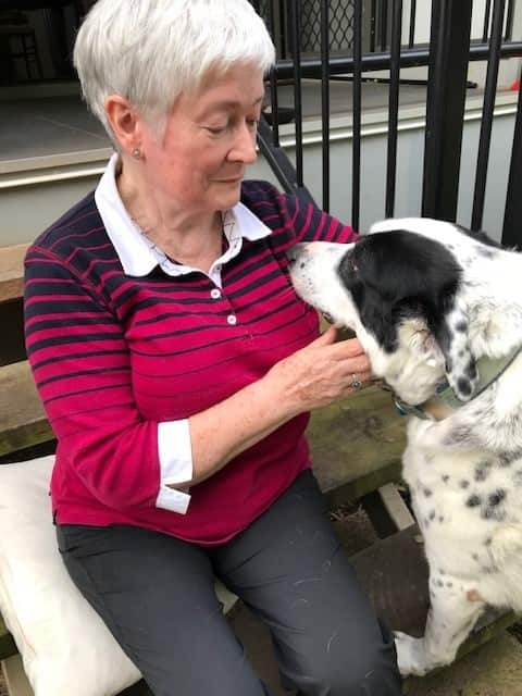 A woman looks into the eyes of her white and black spotty dog